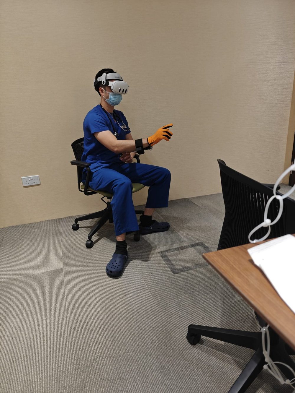 A doctor in scrubs wearing a headset and the HexR glove for the arthritis exam